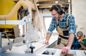Wood worker cutting plywood with a large panel saw in a woodshop
